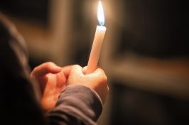 person holding lit candle at direct cremation